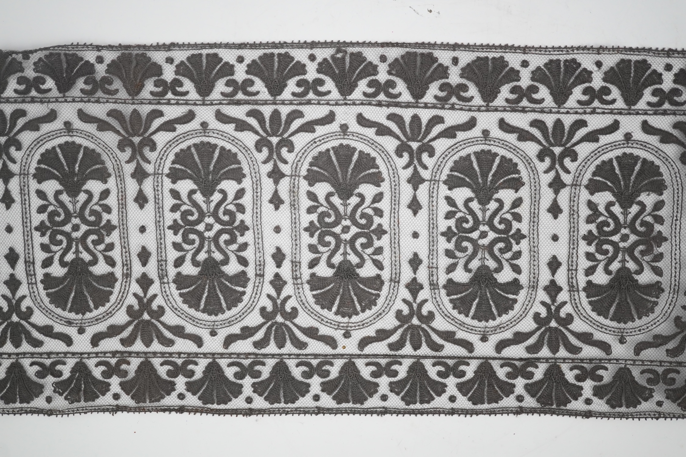 An unusual 19th century decorative length of charcoal grey machine furnishing lace, attributed to Christopher Dresser, together with a similar grey lace bonnet veil, both possibly Nottingham lace, furnishing lace 300cm j